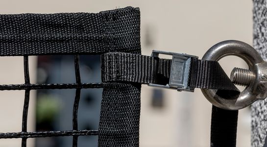 Area confinement net in black with buckled strap fastened to a screw bolted into a wal, detail picture